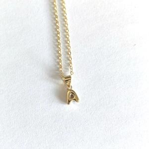 Macro shot of minimalist gold capital letter A pendant necklace with delicate chain link