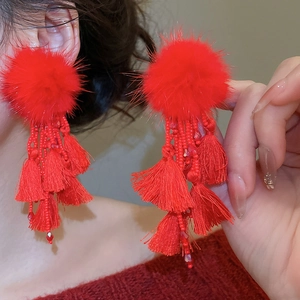 Close-up of elegant red pompom tassel earrings with beaded accents for a festive look