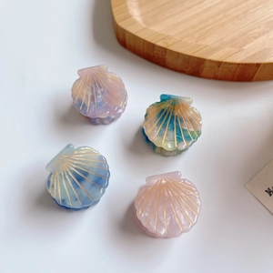 Set of four colorful shell-shaped acetate hair clips with golden marble patterns