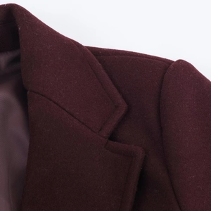 Macro shot showing refined lapel and shoulder seams of the burgundy wool coat