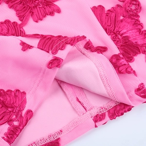 Gros plan d'une robe en dentelle rose montrant les broderies florales 3D et le tulle
