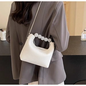 White lychee pattern bag featuring a pearl handle and silver chain strap on a grey blazer