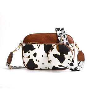 Detail view of quilted patchwork crossbody bag with cow print and circular mini pouch