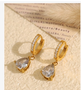 Gros plan de boucles d'oreilles dorées avec anneaux sertis et grand zircon goutte