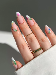 Close-up of long French press-on nails with colorful hand-painted floral patterns and rings