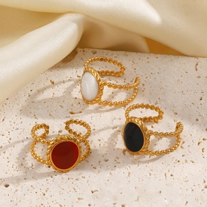 Three minimalist 18K gold plated oval rings with white black and red enamel on sandstone