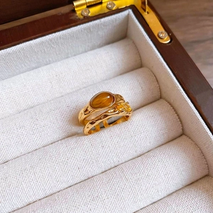 Detailed view of gold-plated tiger eye stone and zircon rings in a jewelry box