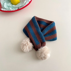 Close-up of blue and brown striped knit scarf featuring soft beige pom-pom details