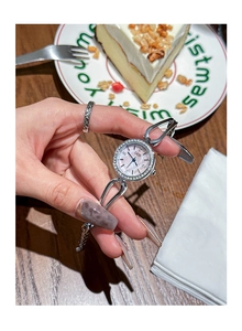 Elegant silver quartz watch with rhinestone bezel worn in a cozy cafe setting