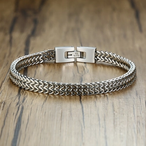 Detailed view of silver stainless steel curb chain bracelet on a wooden texture background