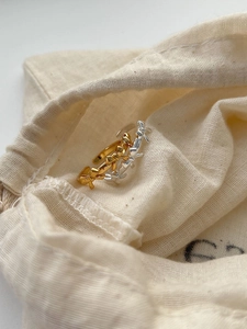 Close-up of gold and silver S925 sterling silver bow rings on a soft linen pouch