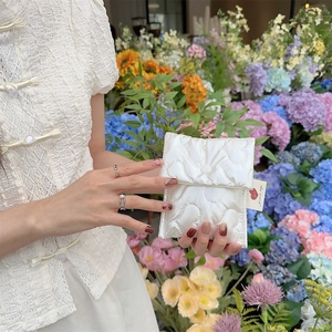 Detail of white quilted sanitary bag with heart patterns and woven side label