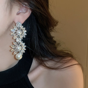 Detail of silver drop earrings with crystal flower petals and dangling faux pearls