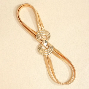 Detail of gold metal elastic belt featuring double geometric ring buckle on beige texture