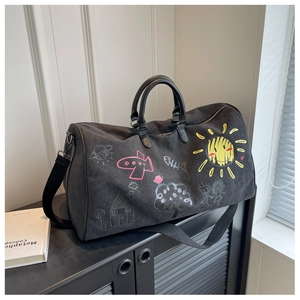 Detail of black canvas travel bag with colorful hand-drawn graffiti on a shelf