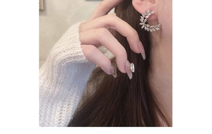 Close-up of elegant silver crescent wheat ear studs with zircon on a model ear