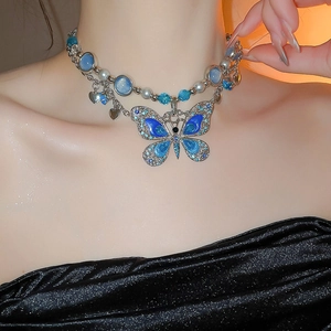 Gros plan du collier pendentif papillon avec émail bleu, cristaux et perles
