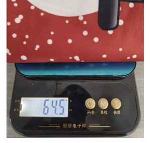 Détail montrant une housse de chaise de Noël de 64,5g pesée sur une balance électronique