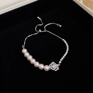 Detailed macro view of the silver adjustable pearl bracelet with a rose pendant charm