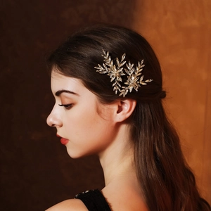 Close-up of a golden leaf hair clip with crystal rhinestones on a model's hair