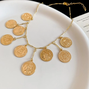 Close-up of gold coin pendant necklace with portrait relief on a white ceramic plate