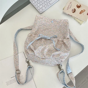 Detail of floral canvas backpack with gingham drawstrings and delicate bow accents