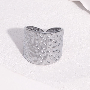 Détail macro d'une bague large ouverte argentée avec texture martelée au style minimaliste