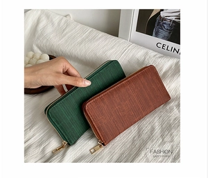 Detail of long striped women's wallet in green and brown with textured leather and gold zipper
