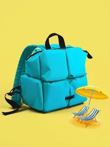Détail du sac à dos matelassé bleu ciel avec poignées noires sur fond jaune vif