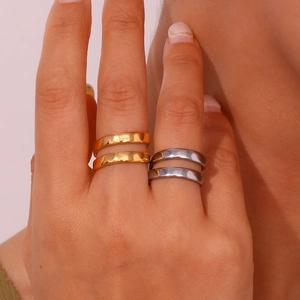 Close-up of minimalist flat band rings in gold and silver finish worn by a model