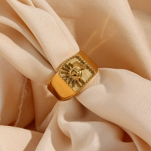 Close-up of a 18K gold plated stainless steel sun pattern ring on beige silk fabric