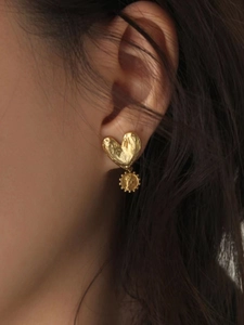 Vintage gold heart earrings featuring a small coin pendant worn by a model