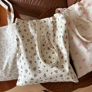 Detailed macro view of three cotton floral canvas tote bags with various flower patterns