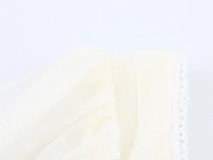 Detailed macro view of cream-colored pleated fabric with delicate lace trim on the edges