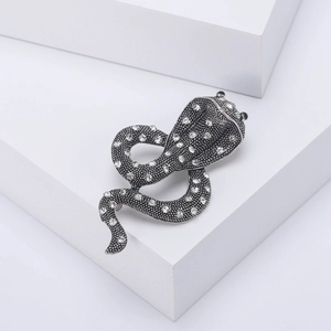 Vintage silver snake brooch with sparkling rhinestones on a white geometric background