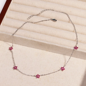 Detail of silver chain necklace with pink rhinestone flowers in a velvet jewelry box