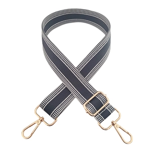 Detail of adjustable gray-blue canvas bag strap with white stripes and gold metal hooks