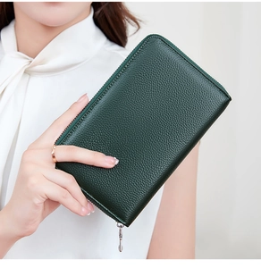 Detail of dark green pebbled leather wallet with silver metal zipper held by a model