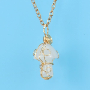 Macro shot of gold wire-wrapped opal mushroom pendant on a thin gold chain