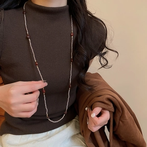 Close-up of vintage tiger eye beaded necklace on dark brown knit sweater texture