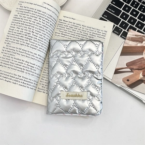 Close-up of silver heart-quilted PU leather passport holder with a brand woven label