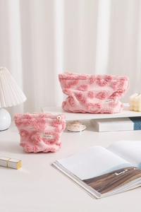 Détail de trousses à maquillage en peluche rose avec textures de cœurs en deux tailles