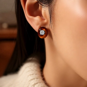 Detailed close-up of a vintage amber resin stud earring with sparkling zircon on model ear