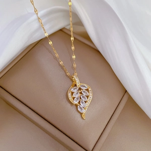 Detail of a luxury gold leaf pendant with crystal micro-paving in a beige jewelry box