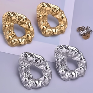 Close-up of irregular textured metal hoop earrings in gold and silver finishes
