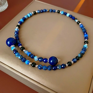 Close-up of geometric beaded necklace with blue agate and silver filigree spacers on leather