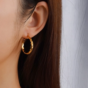Chic boucles d'oreilles créoles dorées torsadées pour femmes portées pour un look élégant