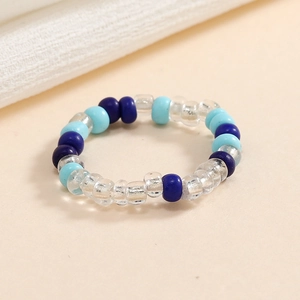 Dettaglio di un anello elastico fatto a mano con perle blu scuro, blu chiaro e trasparenti