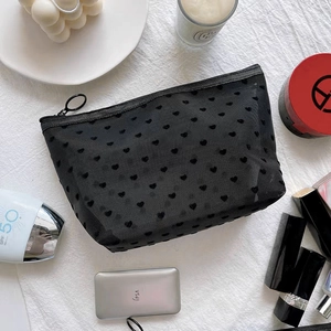 Detail of black mesh makeup bag with flocked hearts, featuring smooth zipper and ring pull