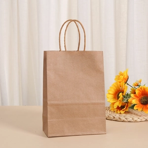 Eco-friendly brown kraft paper gift bag with twisted handles on a warm wooden tabletop